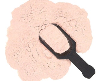 May include: A scoop of light pink powder on a white background. The powder is in a pile and a black plastic scoop is lying on top of it.