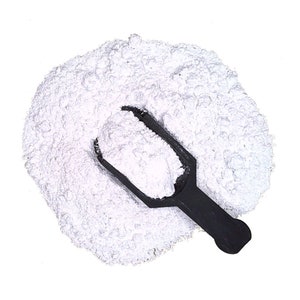 May include: A white powder in a black plastic scoop. The powder is piled high and spills over the edges of the scoop.