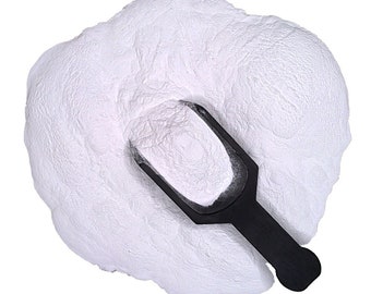 May include: A white powder in a black plastic scoop. The powder is piled high and has a fine texture.