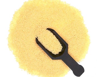 May include: A scoop of uncooked couscous, a type of pasta, in a small black scoop. The couscous is a pale yellow color and is piled high in the scoop.