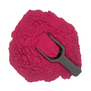 May include: A pile of bright pink powder with a black scoop on top.