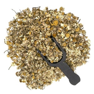 May include: A close-up of dried chamomile flowers, a popular herbal tea ingredient, with a black scoop.