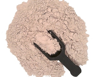 May include: A close-up of a pile of light brown powder with a black plastic scoop. The powder is finely ground and has a slightly grainy texture.