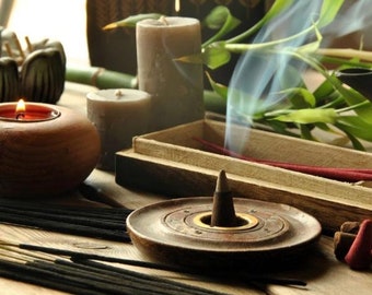 May include: A wooden incense burner with a cone of incense burning, surrounded by incense sticks and candles. The incense burner has a circular design with a small hole in the center for the incense cone. The incense sticks are black and the candles are white.
