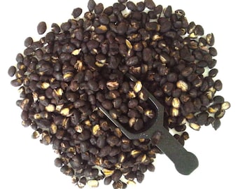 May include: A close-up of a pile of dark brown coffee beans with a black scoop. The beans are scattered on a white surface.