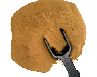 May include: A pile of fine, light brown powder with a black scoop. The powder has a textured surface, and the scoop is partially inserted into the powder. The image is set against a white background, highlighting the powder's color and texture.