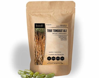 May include: A brown paper bag of "True Tongkat Ali" dietary supplement with a label featuring text and an image of roots. Several green capsules are scattered in front of the bag. The label states the product boosts hormones, immunity, and lowers stress.