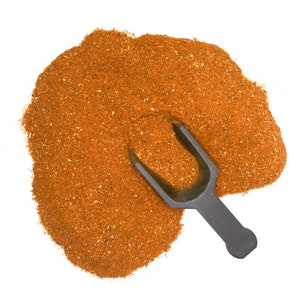 May include: A pile of orange-brown spice blend with a black plastic scoop.