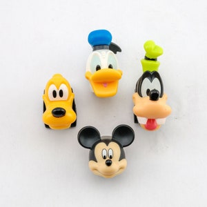 Op de afbeelding: Vier plastic figuren van Disney-personages: Mickey Mouse, Donald Duck, Goofy en Pluto. De figuren zijn geel, zwart, blauw en bruin.