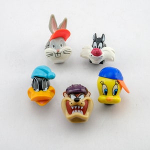 May include: Five cartoon character figurines, including Bugs Bunny, Tweety Bird, Taz, Daffy Duck, and Sylvester the Cat. The figurines are made of plastic and are brightly coloured.