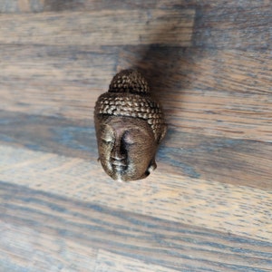 Op de afbeelding: Een klein, goudkleurig, 3D-geprint Boeddha-hoofdbeeld.