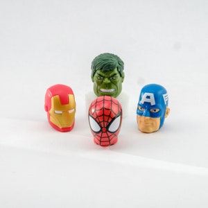 Peut inclure: Figurines de tête de super-héros : un Hulk vert, un Iron Man rouge, un Spiderman rouge et bleu et un Captain America bleu.