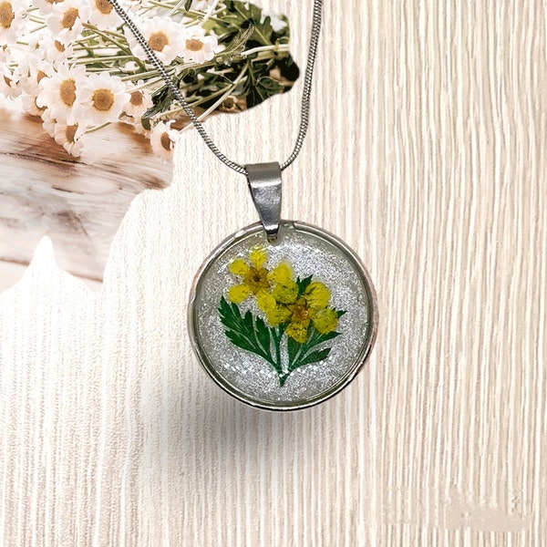 Pendentif femme rond incrustation de véritables fleurs jaunes et mini feuilles dans un cerclage argent vieilli. Cadeau pour femme