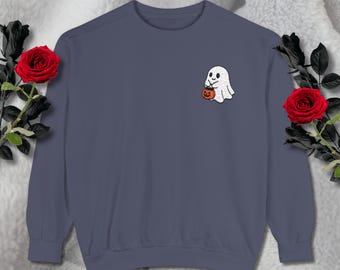 May include: A navy blue sweatshirt featuring a small embroidered ghost holding a jack-o'-lantern. The ghost is white with black eyes and a smiling mouth. The sweatshirt is a solid color, perfect for Halloween.