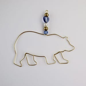 May include: Gold wire bear ornament with blue and white beads hanging from the top.