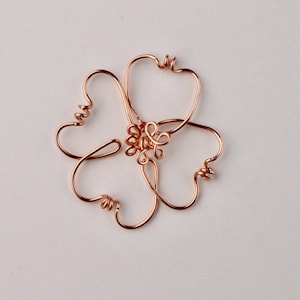 May include: A copper wire flower with five petals and a center made of twisted wire.