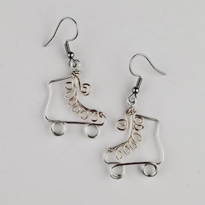 May include: A pair of silver roller skate earrings with gold wire details. The earrings are made of wire and have a hook fastening.