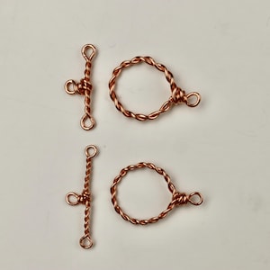May include: Two sets of copper wire clasps. Each set includes a twisted wire toggle clasp and a twisted wire ring clasp.