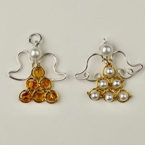 May include: Two wire angel ornaments with wings and a beaded body. One angel has a gold body with amber beads and the other has a gold body with white beads.