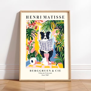 May include: A framed art print featuring a black and white dog reading a newspaper, set against a colorful backdrop of tropical plants and flowers. The print is labeled "HENRI MATISSE" and "BERGGRUEN & CIE, 70 Rue de l'Université Paris 75007".