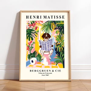 Peut inclure: Une affiche encadrée représentant un chien lisant un journal sur des toilettes, avec un fond coloré de plantes tropicales. Le titre "HENRI MATISSE" est en haut, et "BERGGRUEN & CIE" avec une adresse en bas.