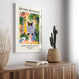 Puede incluir: Una impresi&oacute;n art&iacute;stica enmarcada al estilo de Henri Matisse, que representa a un perro leyendo un peri&oacute;dico. La obra presenta un fondo colorido con plantas tropicales. Incluye el texto "HENRI MATISSE" y "BERGGRUEN & CIE".