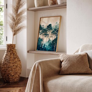 May include: A framed print of a forest scene with tall, dark green trees and a light blue sky. The print is hanging on a white wall above a beige couch with a brown throw pillow.