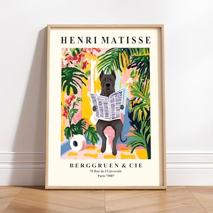 May include: A framed art print depicting a dog reading a newspaper, set against a vibrant background of tropical plants and flowers. The print includes the text "HENRI MATISSE" and "BERGGRUEN & CIE". The artwork has a whimsical and artistic style.