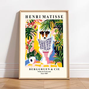 May include: A framed art print featuring a dog reading a newspaper, in a colorful, Matisse-inspired style. The print includes the text "HENRI MATISSE" at the top and "BERGGRUEN & CIE" with an address at the bottom. The dog is white with brown and black markings.