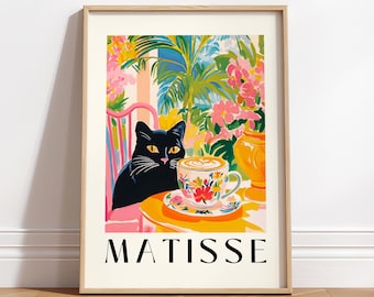 May include: A framed art print featuring a black cat, a cup of coffee, and the word "MATISSE". The artwork has a colorful, floral design with a yellow table and a pink chair. The cat is looking at the coffee.