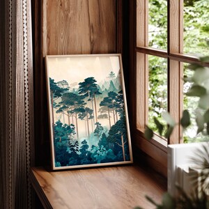May include: A framed print of a forest scene with tall, dark green trees and a misty background. The print is in a light wood frame and is hanging on a wooden wall.