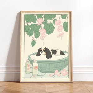 Pode incluir: Impressão artística emoldurada com um Cavalier King Charles Spaniel relaxando em uma banheira. O cão tem pelo preto e branco. A impressão apresenta uma banheira verde clara, flores rosa e folhas verdes. Duas garrafas estão no lado esquerdo da banheira.