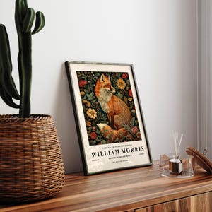 May include: A framed print featuring a fox surrounded by flowers. The print is titled "William Morris" and includes the text "Cotton Prints Exhibition, History of Textile Design, The Art of the 19th Century".