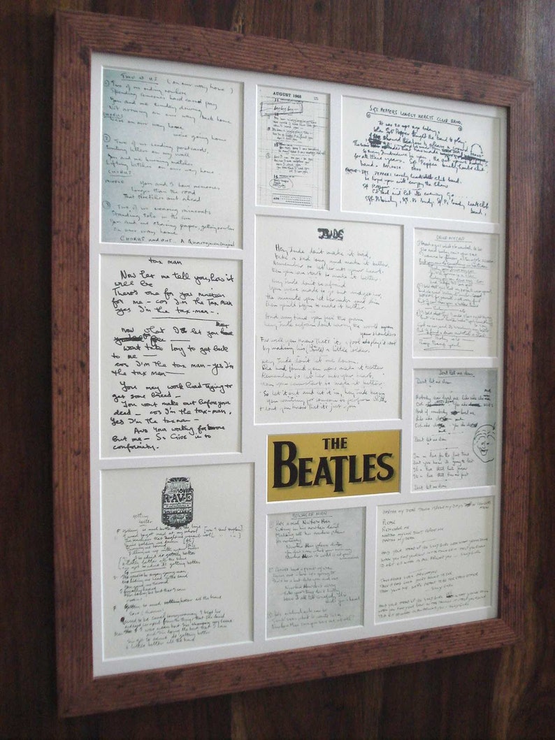 Puede incluir: Una colecci&oacute;n enmarcada de letras escritas a mano de los Beatles, incluyendo "Hey Jude", "Get Back", "She's Leaving Home" y "Taxman". Las letras se muestran en un marco blanco con un borde dorado y un logotipo dorado de "The Beatles".