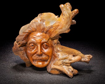 May include: A wooden sculpture of a man's face carved into a piece of driftwood. The sculpture has a whimsical and realistic style.