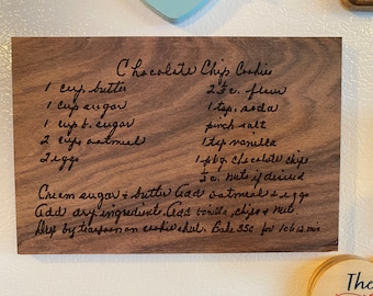 May include: A wooden plaque with a handwritten chocolate chip cookie recipe. The recipe includes ingredients like butter, sugar, flour, and chocolate chips. The plaque is a great way to display a family recipe or a favorite baking recipe.