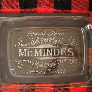 May include: A clear glass baking dish with handles, featuring an engraved design with the text "Ryan & Karen Mc Mindes August 27, 2022".