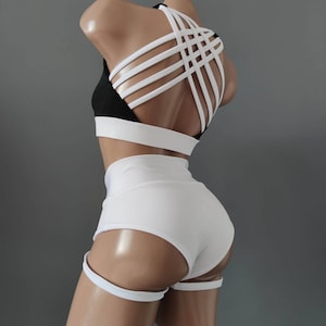 Pode incluir: Conjunto de dança branco e preto com um top de tiras cruzadas e shorts de cintura alta. Os shorts têm um detalhe de alça de perna.