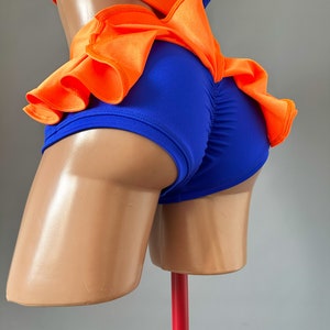 May include: A blue and orange dance costume with a ruffled skirt. The costume is made of a stretchy fabric and has a fitted bodice.