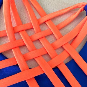May include: A blue and orange swimsuit with a criss-cross design on the back.