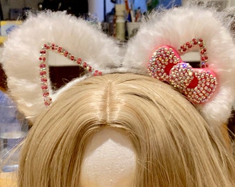 White fluffy cat ears with hot pink bow. Blinged with many rhinestones.