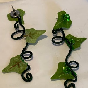 May include: A pair of green ivy leaf earrings with black wire vines and green glitter accents.