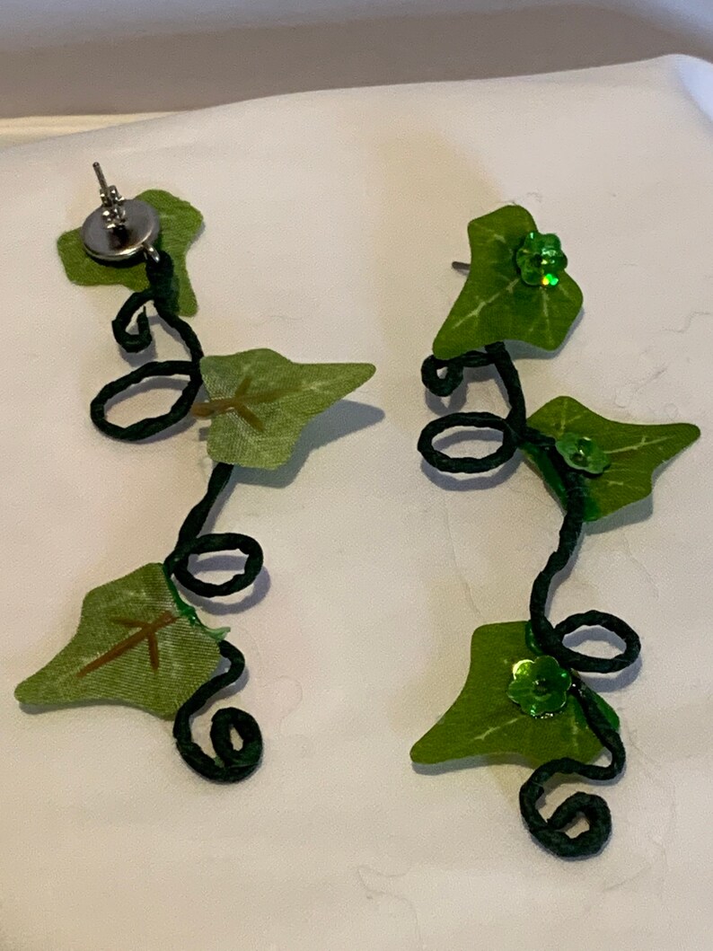 May include: A pair of green ivy leaf earrings with black wire vines and green glitter accents.