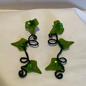 May include: A pair of green leaf earrings with black wire vines and green glitter accents.