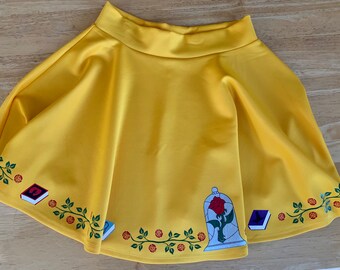 Puede incluir: Una falda amarilla con un diseño floral que presenta una rosa en una cúpula de vidrio, libros y enredaderas.