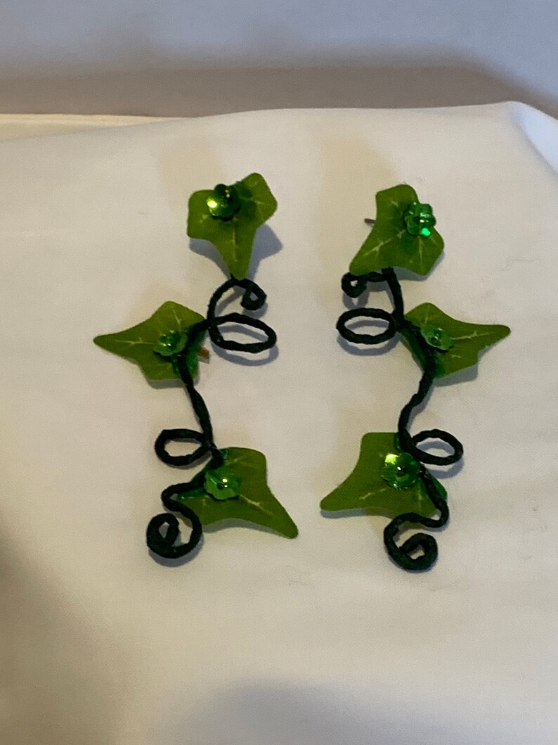 May include: A pair of green leaf earrings with black wire vines and green glitter accents.