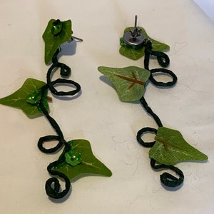 May include: A pair of green leaf earrings with a black wire vine design and green sequins. The earrings are dangling and have a silver post.