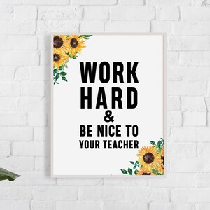 May include: White framed poster with black text that reads "Work Hard & Be Nice To Your Teacher". The poster is decorated with yellow sunflowers and green leaves.