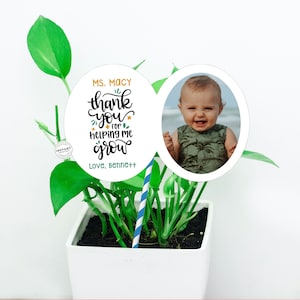 May include: A white circle with the text "Ms. Macy thank you for helping me grow Love, Bennett" and a smaller white circle with a photo of a smiling baby boy. The circles are attached to a blue and white striped stick.