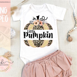May include: White baby onesie with a graphic of a pumpkin with leopard print and gold glitter. The pumpkin has flowers and the text "Little pumpkin" on it.